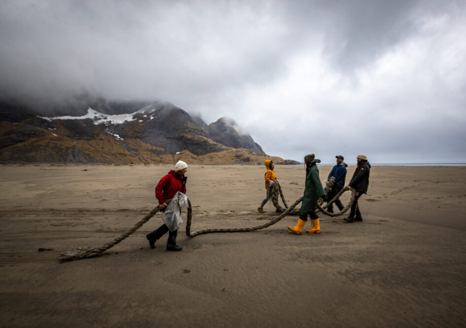 Fem strandryddere har funnet en lang og tung trosse som de drar med seg til oppsamlingsplassen for marint avfall.